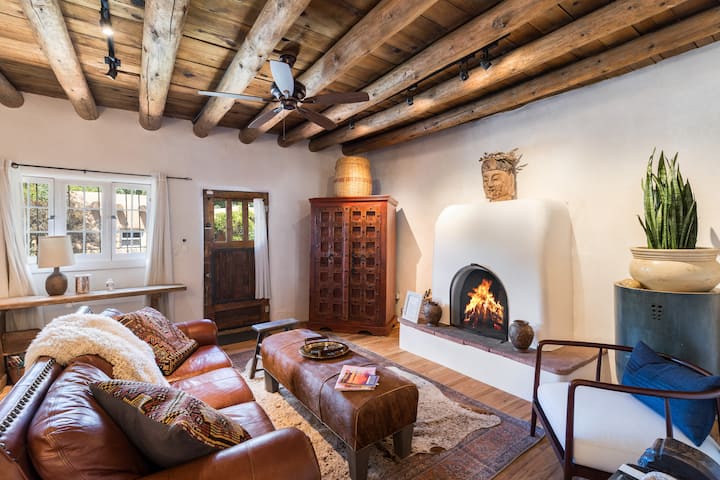 Traditional Santa Fe adobe with log viga ceiling, kiva fireplace, and leather sofa