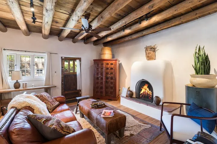 Traditional Santa Fe adobe with log viga ceiling, kiva fireplace, and leather sofa